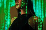 A photo of a young woman with computerized binary code numbers all over the wall in the background and on her face showing a glitch in the matrix.