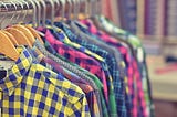 Assorted colorful plaid shirts hanging next to each other on a rack