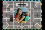 Channel 9 test pattern from the 1970’s, showing a test pattern with a girl holding chalk playing noughts and crosses, next to a clown doll.