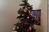 A fully decorated Christmas tree with a variety of ornaments in front of a white wall. The star from Super Mario Bros. is the topper.