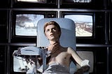 David Bowie in the film The Man Who Fell To Earth watching multiple TV screens