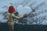 wooden man toy with red hat making a snow heart