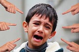 A boy crying as people point fingers at him