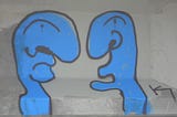 Two blue figures painted on a wall in dicussion.