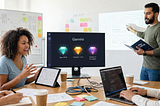 The image depicts a collaborative workshop where a woman gestures toward an AI “Spec Brief Coach” on a laptop while a colleague reviews a “Provocative” prototype variation on a tablet. The workspace is scattered with sticky notes for “Vibe Coding” and “CUJs,” alongside a background note reflecting the goal that every digital workshop board should become a persistent AI Gem.