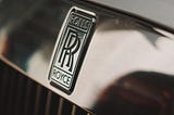 Photo of the “Double R” logo on the front of a Rolls Royce front grill.