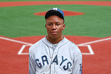 Negro League star Josh Gibson in front of a baseball field.