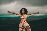 photo of woman in colorful dress with spread arms in nature