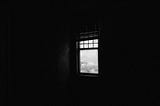 black walls, and an uncurtained window.