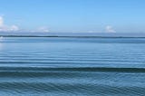 Ocean landscape with shallow wave and clouds on horizon.