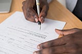 A person’s hands holding a fountain pen, signing a document