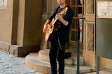 A photo of the author playing guitar on the street.