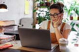 A woman sitting in front of her laptop, preparing user research, smiling.