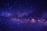 Image of the milky way at night. It shows a purple, clear sky. Taken from the Earth.