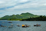 View of the sea with fishing boats and a volcanic island in the distance.