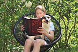 A girl reads ‘Six of Crows’ with a dog on her lap.