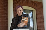 Image of a lady holding her own book that has been published.