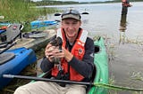 Biologist sitting in a kayak holding a ring-necked duck