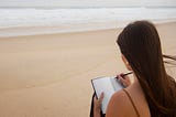 Woman writing on a beach