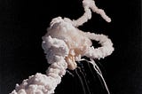 Color photograph of Challenger breaking apart in the air with visible plumes of steam.