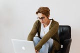 woman sitting in chair while using laptop