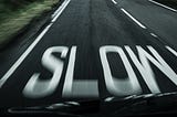 View from a fast-moving car, “slow” painted on road