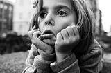 A girl lying on the ground with her head in her hands making a tired face.