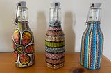 Three small glass bottles with intricate designs painted on them.
