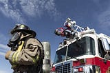 A firefighter in front of a fire truck, probably thinking about posting on Twitter