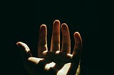 An open palm facing upwards with a dark and shadowy background.