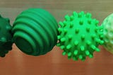 Four silicone-covered magnets in different shades of green, with different surface textures.