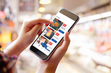 Image of a person using the Lidl Plus app on their smartphone while browsing exclusive discount.