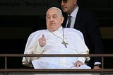 Pope Francis, seated in a wheelchair, gives a thumbs-up to the crowd from the balcony of Gemelli Hospital in Rome.