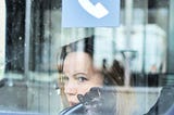 woman stares out of a window with reflective surfaces