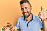 A man holding a plate of chocolate chip cookies. Courtesy of shuterstock.com / Krakenimages.com