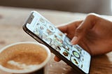 Mobile phone showing instagram feed and a cup of coffee
