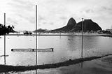 Uma foto em preto e branco que mostra o Pão de Açúcar e a baía de Guanabara com muitos barcos no fundo,