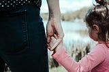 Little girl holding onto a woman’s hand