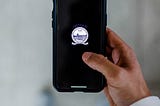 A person holding a smartphone in one hand which shows the emblem of VIT University