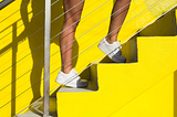 Close-up shot of Person’s Legs Standing on Yellow Stairs. How stair climbing transforms your heart health and body composition