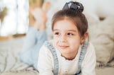 A little girl with a book, looking off into the distance whimsically