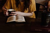 woman reading a book at a table