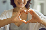 Woman smiling extending her hands in the shape of a heart