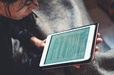 A woman reading an article on a tablet.