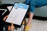 A woman holding a clipboard with her resume.