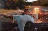 A girl leans out the back of a vehicle.