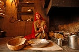 An Indian woman makes bread. Her shelves are at a low height, which is common in floor-sitting cultures.