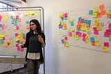 A person talking to a group in a workshop, surrounded by sticky notes.