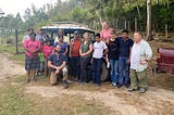 A group of adults and children pose for a photo in front of an offroad vehicle on a woodland track in Honduras