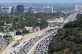 Traffic in Los Angeles under cheery sun, miles of cars stretching out to the horizon